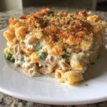A generous serving of creamy tuna pasta bake featuring macaroni, peas, and a golden, crunchy breadcrumb topping.