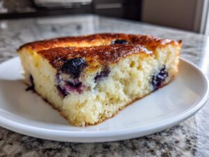 Close-up of a thick slice of blueberry sheet pan pancakes with a golden-brown top.