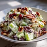 Close-up of a creamy celery salad featuring large chunks of celery, pecans, and dried cranberries.