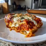 A close-up of a generous slice of crockpot ravioli lasagna layered with cheese and rich tomato sauce.