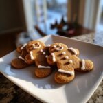 Three freshly baked gingerbread cookies decorated with simple white icing smiles and buttons.