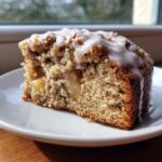 Close-up of a moist slice of jewish apple cake topped with white vanilla glaze.