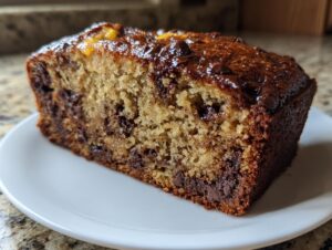Close-up of a moist slice of chocolate chip banana bread showing rich texture and melted chocolate chunks.