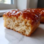 Close-up of a soft maple donut bars square showing the fluffy interior and thick, shiny maple glaze topping.