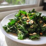 A close-up of a bright green kale salad topped with sliced almonds and grated cheese.