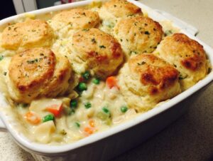Close-up of a baked chicken pot pie casserole topped with golden biscuits and sprinkled with parsley.