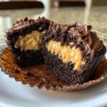 Close-up of a chocolate peanut butter cupcake cut in half showing the rich peanut butter filling.