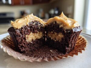 A chocolate peanut butter cupcakes cut in half showing the rich chocolate cake, peanut butter filling, and peanut butter frosting.