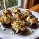 Seven perfectly baked crab stuffed mushrooms with golden, crispy topping served on a white platter.