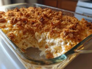 A close-up of creamy chicken noodle casserole baked in a glass dish with a golden, crunchy breadcrumb topping.