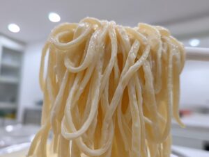 Close-up of thick strands of pasta coated in creamy cottage cheese alfredo pasta sauce being lifted.