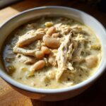 Close-up of a bowl of creamy white chicken chili, featuring shredded chicken and white beans in a rich sauce.