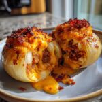 Two halves of a firecracker bacon cheddar cheeseburger stuffed onion bomb, oozing melted cheese and savory filling.