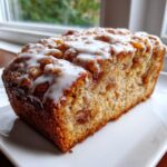 Close-up of a moist slice of country apple fritter bread topped with cinnamon streusel and white glaze.