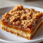 A single, delicious square of carmelitas dessert showing a thick caramel layer and crumbly topping.