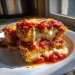 Two stacked pieces of crispy, breaded eggplant parmesan oozing melted mozzarella and topped with rich marinara sauce, made using a healthy air fryer eggplant parmesan recipe.