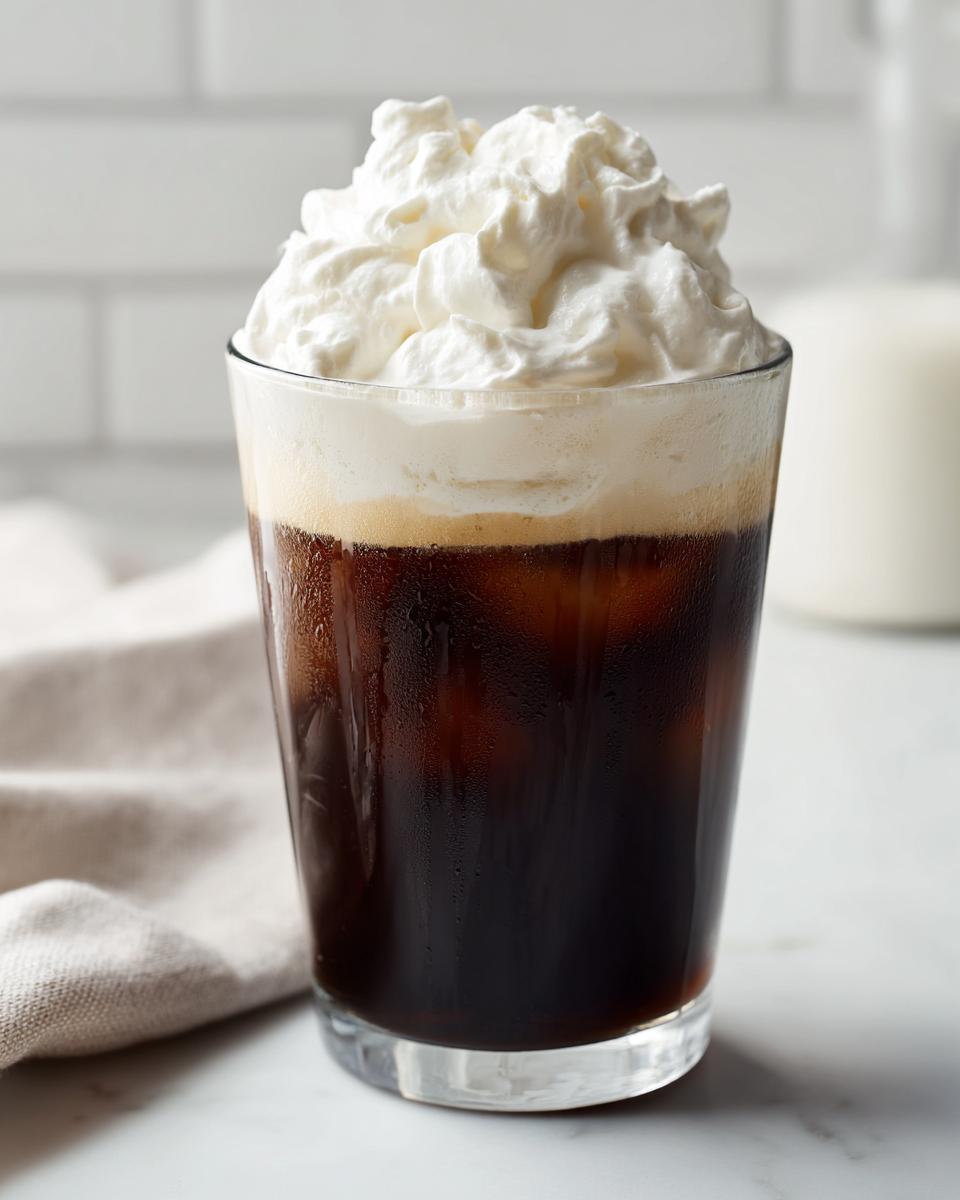 Close-up of iced coffee topped with a generous layer of thick, fluffy cold foam.