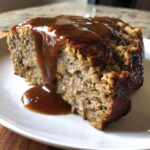 A close-up of a moist slice of meatloaf with mushroom gravy generously poured over the top.