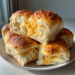 A stack of freshly baked mini grilled cheese Hawaiian rolls showing melted orange cheese inside the soft bread.