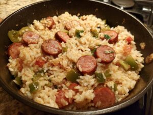 Close-up of flavorful sausage and rice cooked together in a black skillet with green peppers.
