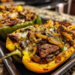 Close-up of a baked yellow bell pepper half filled with steak, onions, mushrooms, and melted cheese, ready to eat philly cheesesteak stuffed peppers.