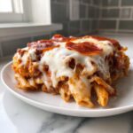 A close-up of a serving of pizza pasta bake, covered in melted mozzarella cheese and pepperoni slices.