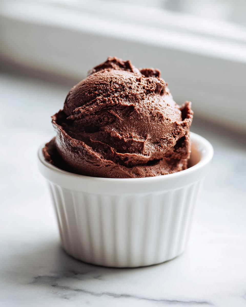 A perfectly scooped portion of rich, dark chocolate mousse served in a white ramekin.