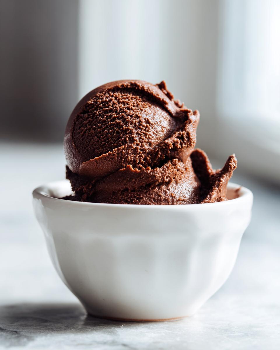 A perfect scoop of rich, dark chocolate mousse served in a small white bowl.