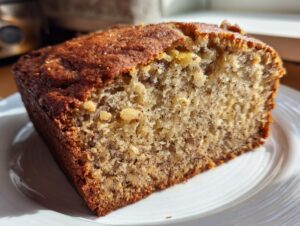 Close-up of a thick slice of sugar free banana bread showing a moist crumb texture and visible nuts.