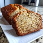 Close-up of a sliced loaf of moist greek yogurt banana bread featuring visible walnuts.