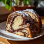 Two slices of moist german marble cake showing beautiful chocolate and vanilla swirls, dusted with powdered sugar.
