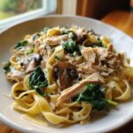 A close-up of a bowl of slow cooker chicken fettuccine with mushrooms and spinach in a creamy sauce.