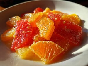 Close-up of vibrant orange and red citrus segments glistening in a white bowl, perfect for a citrus salad.