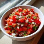 Close-up of a white bowl filled with vibrant, freshly chopped Authentic pico de gallo ingredients.