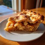 A close-up of a generous slice of Classic apple pie from scratch showing thick apple filling and golden, flaky crust.