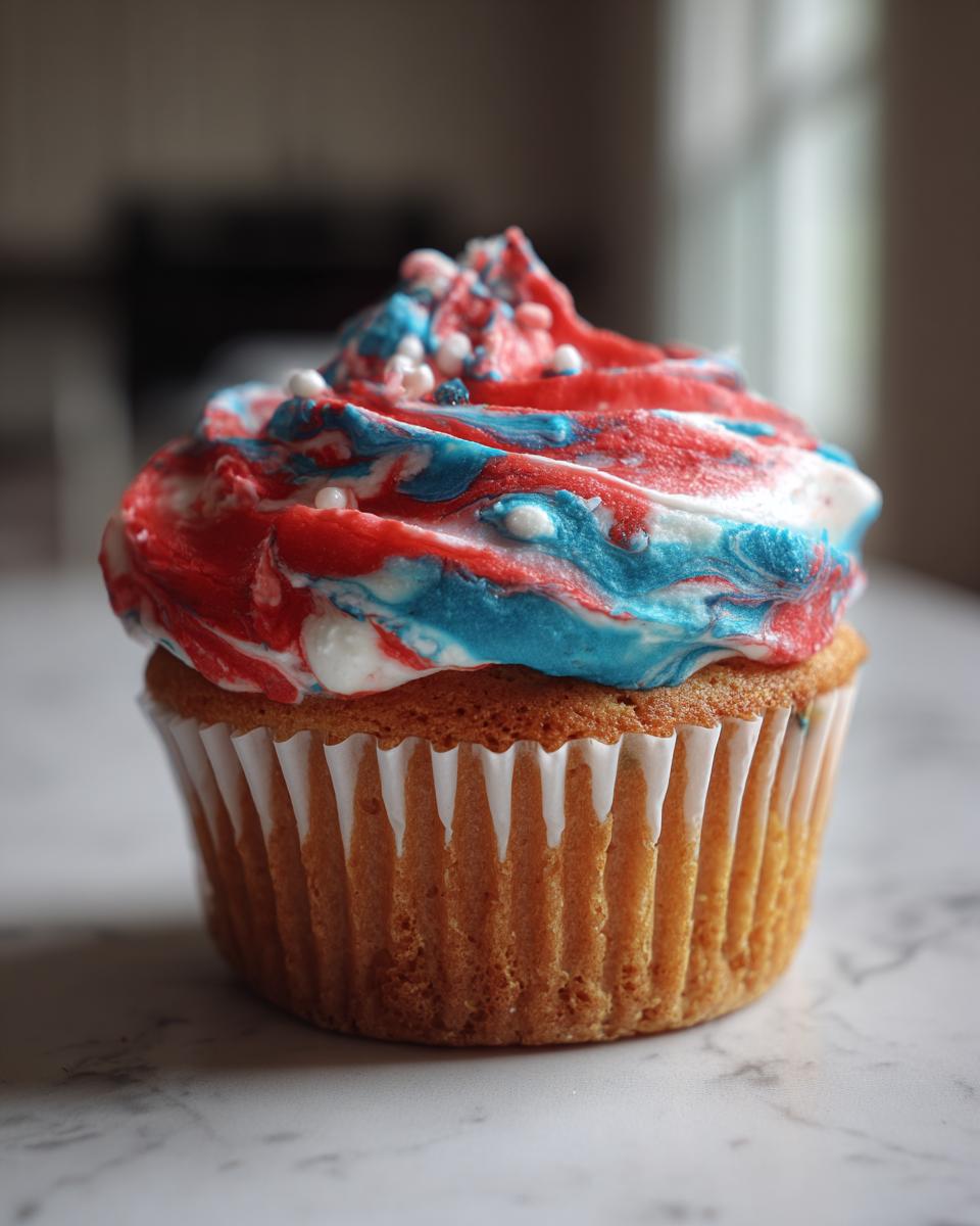 Close-up of a vanilla cupcake with red, white, and blue marbled frosting, perfect for International Nurses Day cupcakes.