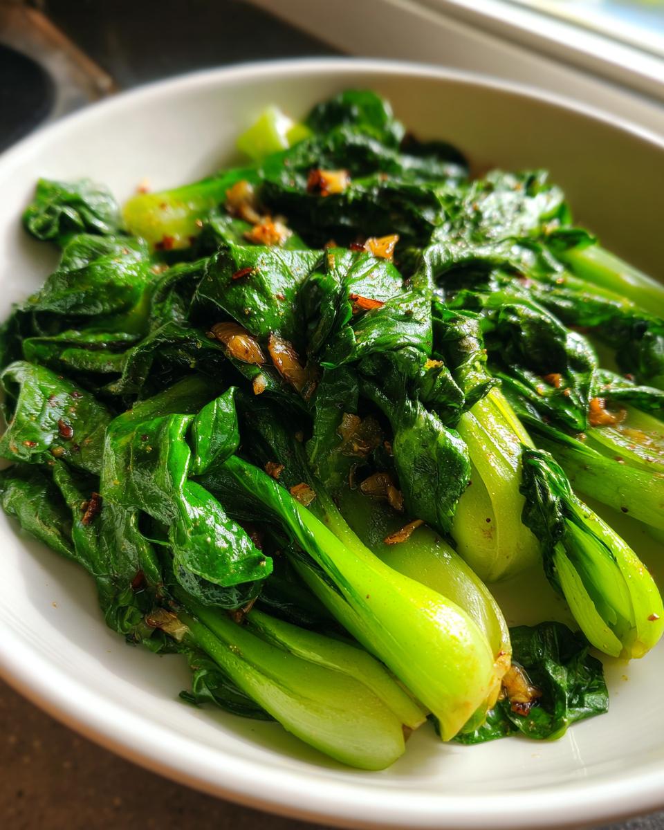Close-up of vibrant green Sautéed bok choy with garlic served in a white bowl.